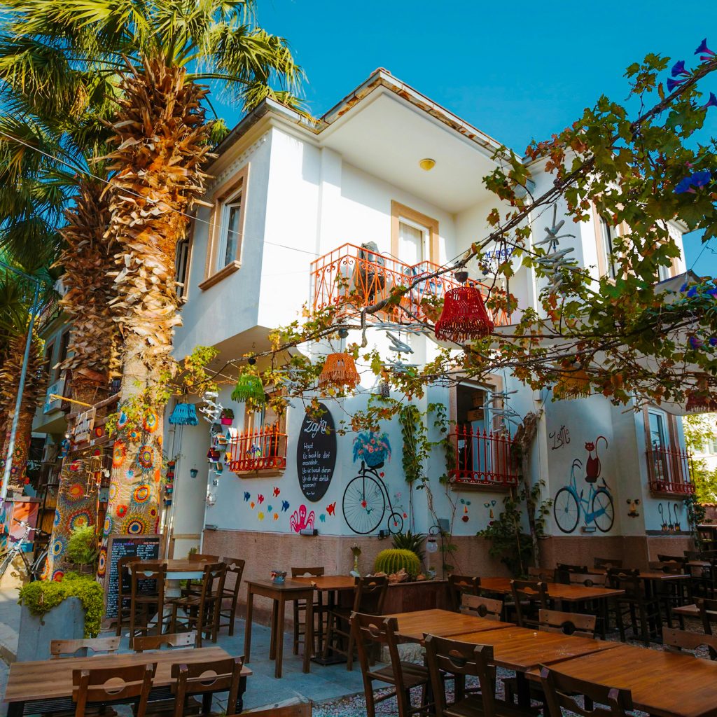 Cozy outdoor café with artistic murals and palm trees in Balıkesir, Turkey.