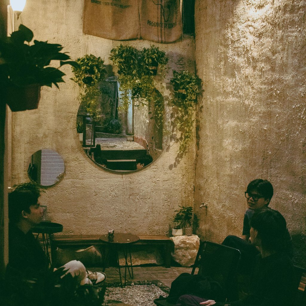 Three friends enjoying a cozy, urban cafe setting with greenery and soft lighting.